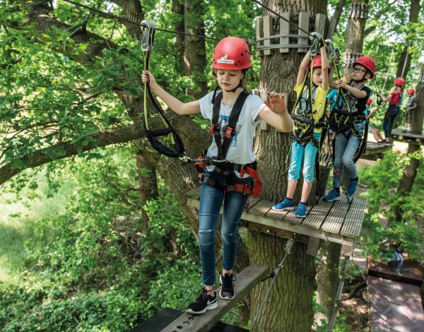 Mitsch�lerInnen einer Schulklasse klettern in Kletterausr�stung durch den Hochseilgarten