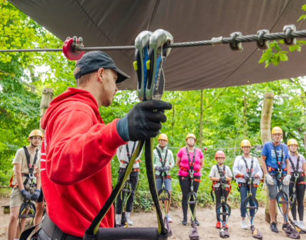 Junger Mann, der Gsten eine Einweisung in das Klettersystem gibt