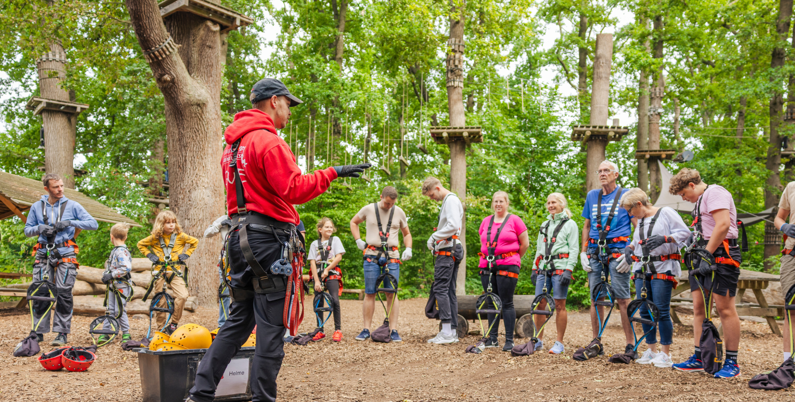 Ein Mitarbeiter des Seatree Kletterparks unterweist eine Gruppe Jugendlicher im Umgang mit den Sicherungssystemen