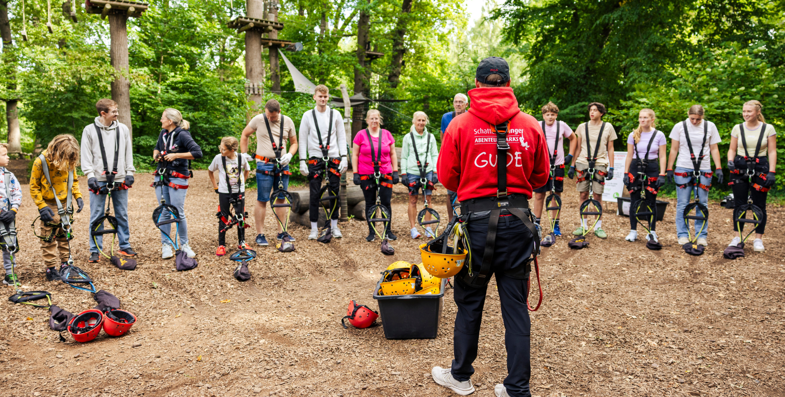 Ein Kletterguide im Fokus, der gerade einer Gruppe eine Einweisung gibt